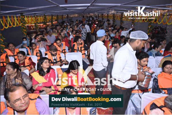 Guests wearing life jackets and receiving refreshments on a Dev Diwali cruise